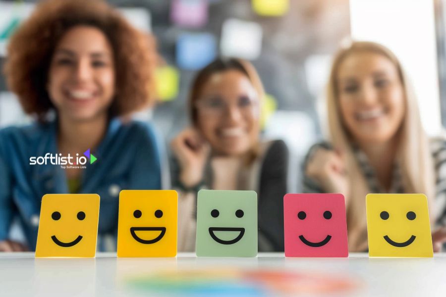 Three women smiling behind colorful smiling face cards in various expressions.