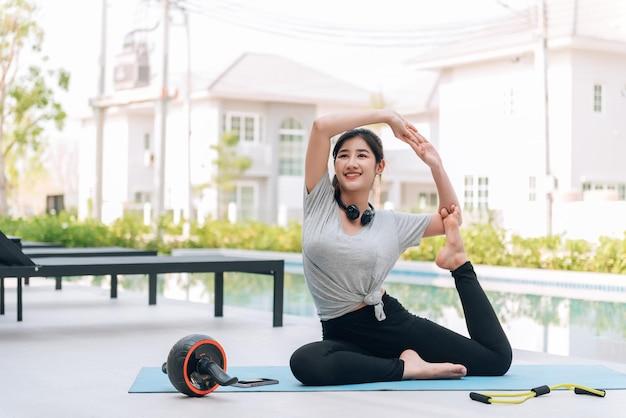 Free photo happy asian woman stretching exercise and yoga workout in the morning at home outdoor