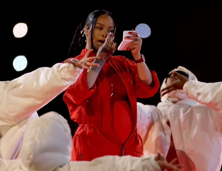 Rihanna using a Fenty Beauty product during her Super Bowl performance