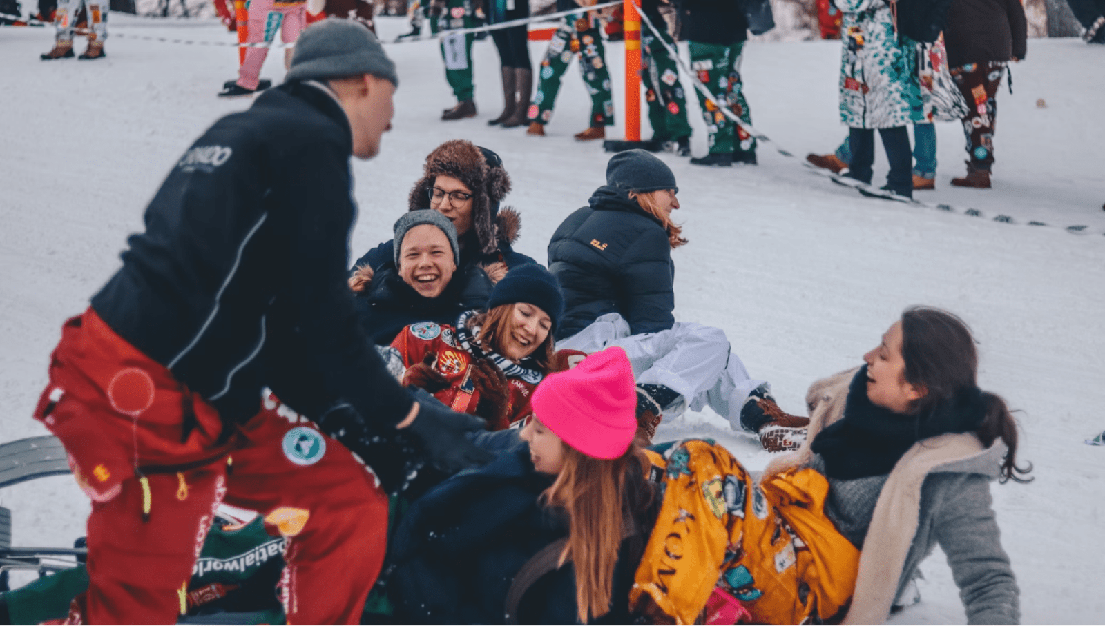 Group of winter sports athletes laugh while sitting on the snow