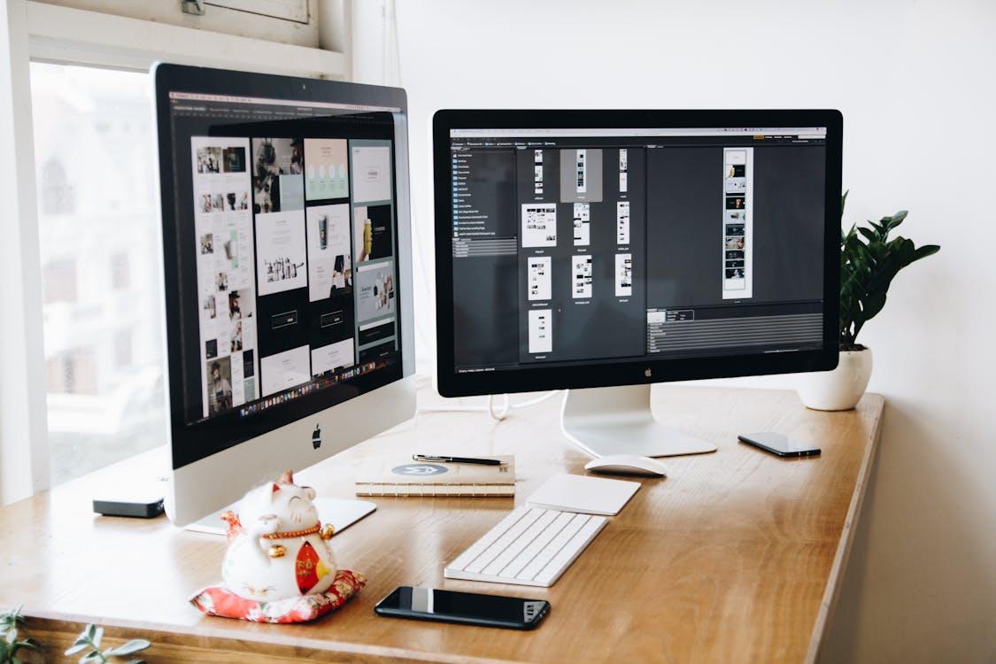 Free Two Imac's With Keyboard and Phones on Desk Stock Photo