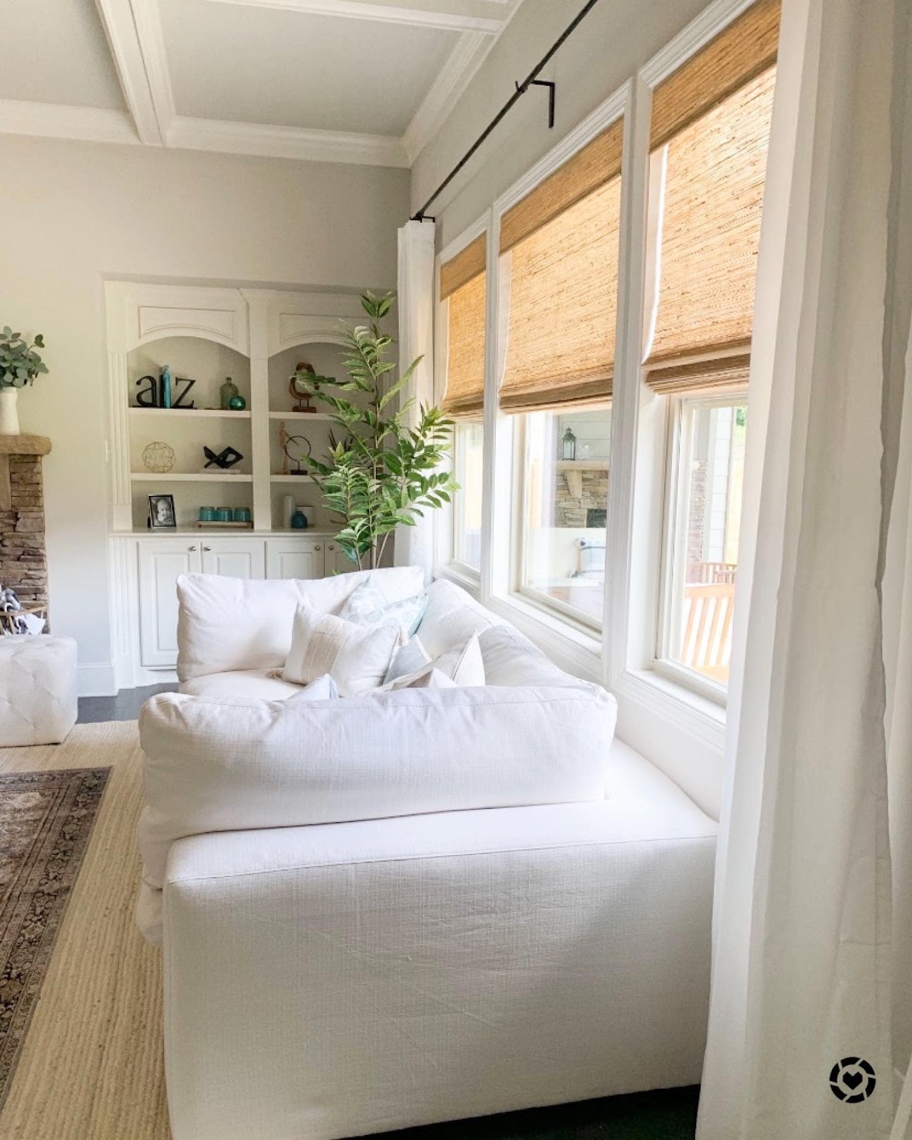 Woven roman shades behind white couch with plant in background