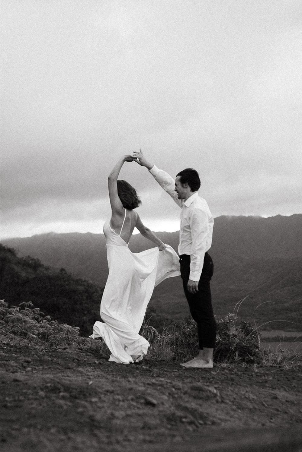 wedding couple twirling on a mountain with bride wearing a simple hiking dress by Shikoba Bride