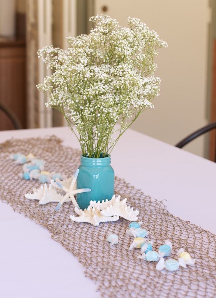 white flowers in blue vase with seashells