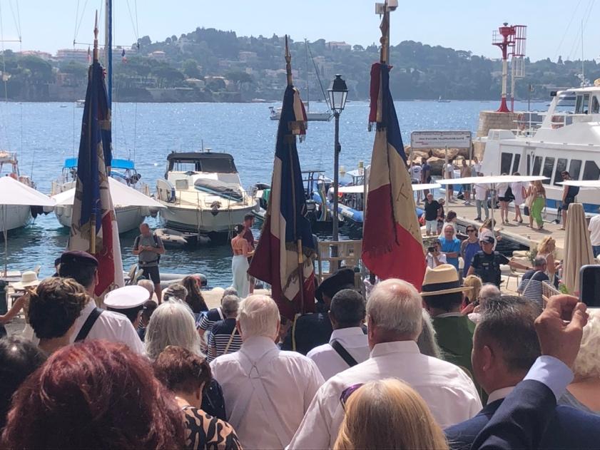 A group of people standing on a dock with flags

Description automatically generated