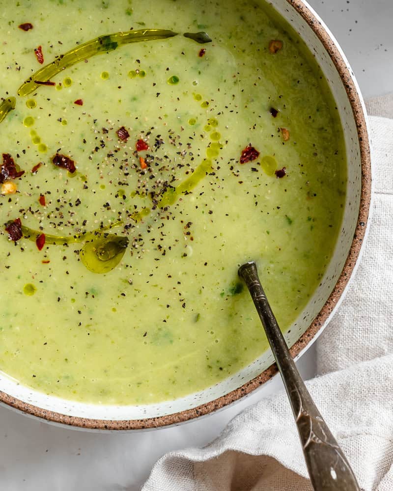 a bowl of vegan zucchini soup in a white bowl.