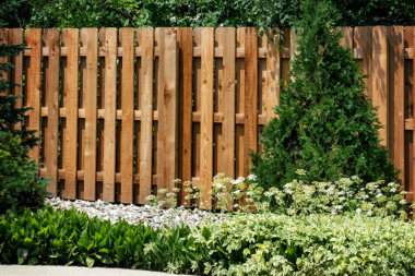 comparing common fencing materials wood fence with landscaping foliage custom built michigan
