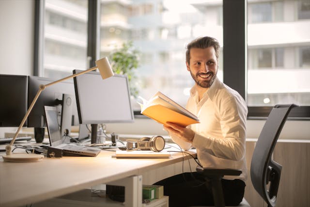 A man holding a book in his office table