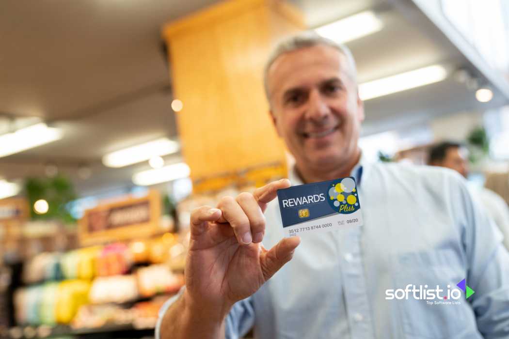 Smiling man holding rewards card in store, shelves with products