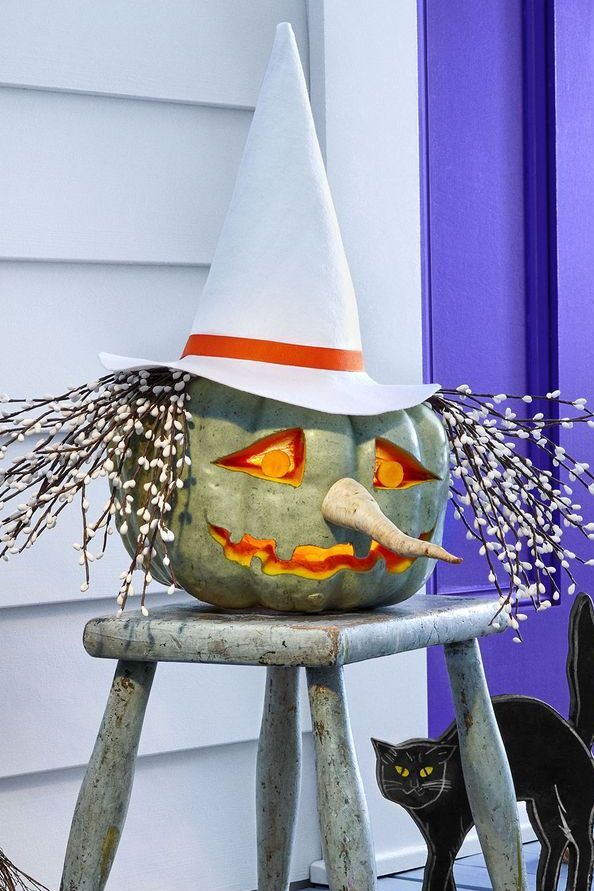 pumpkin carving ideas, pumpkin carved to look like a witch with a white hat and faux blooms for hair