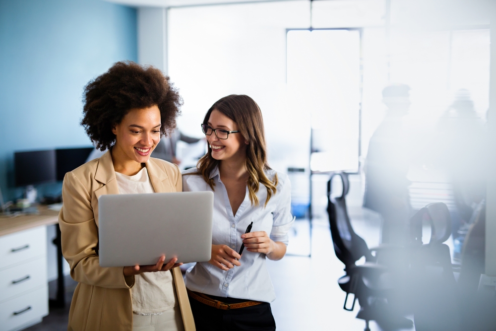 two staff members discussing something on a laptop