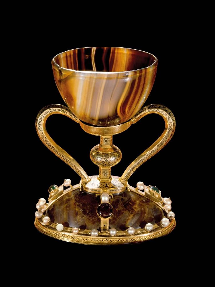 An ornate golden chalice with stones on the bottom