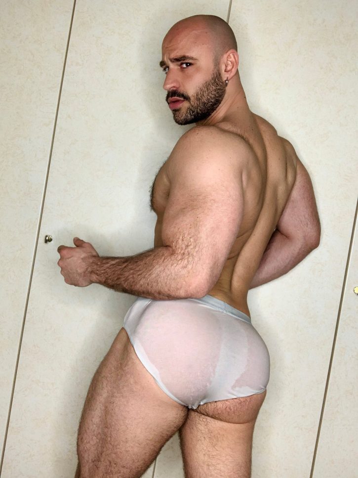 Mister Caccamo in wet white underwear briefs facing away from the camera showing off his gay muscled bubble butt between the wet fabric smirking over his shoulder