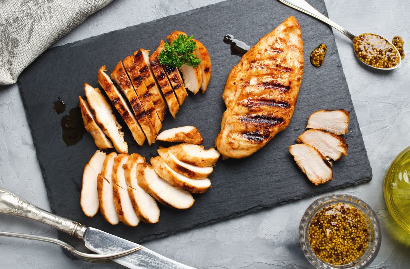 Grilled chicken fillets on a charred wooden board.