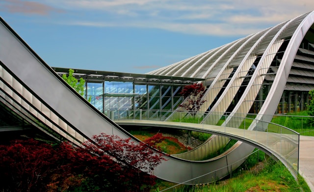 A bridge over a spiral building with a lot of plants all around