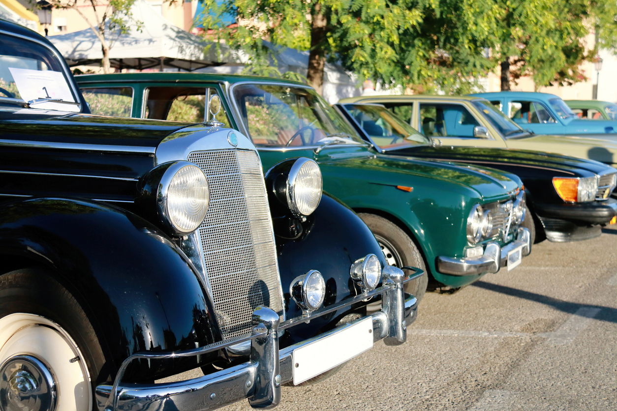 A line of pre-1985 classic cars parked in the sun.