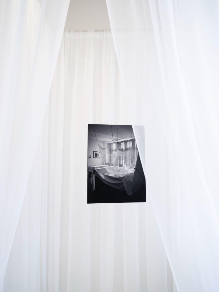 A black and white photo on a white curtain Description automatically generated