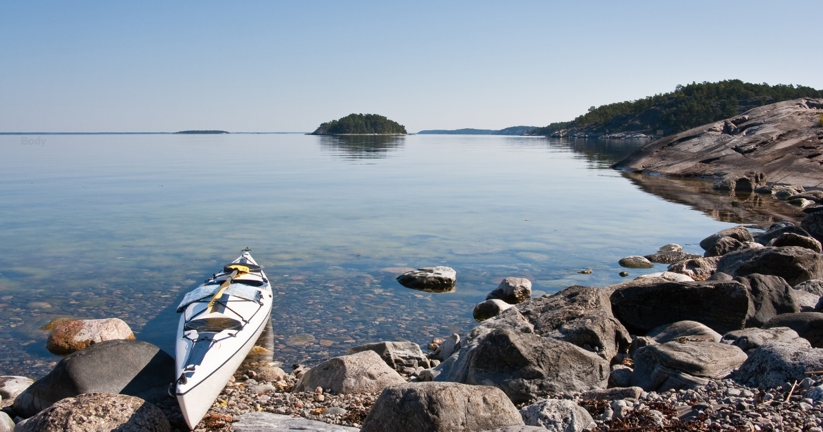 Sea kayak along a scenic Swedish archipelago with blue waters and distant islands.