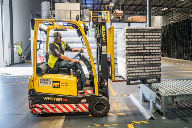 An operator driving a forklift in a warehouse, transporting supplies.