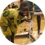 A young child drinking water from a faucet

Description automatically generated