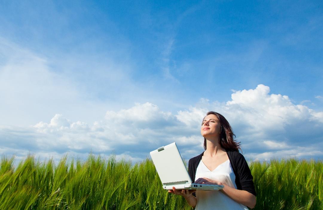 A person holding a computer in a field

Description automatically generated