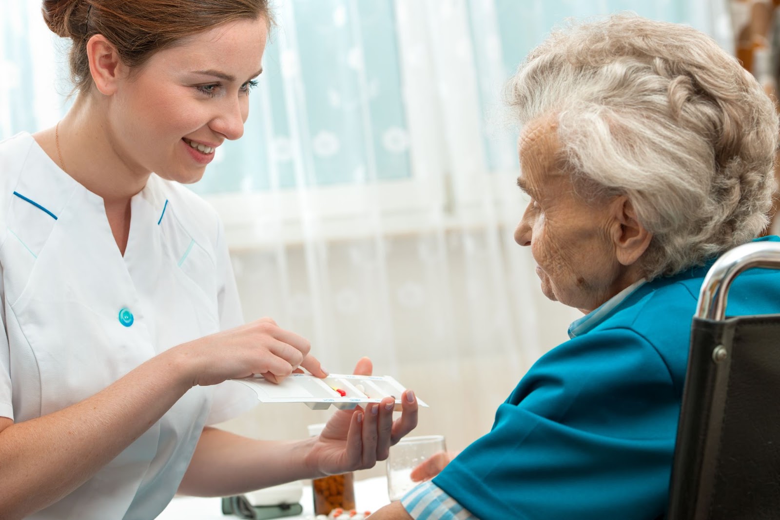 A caregiver in an assisted living community helping a resident with limited mobility by administering medication.