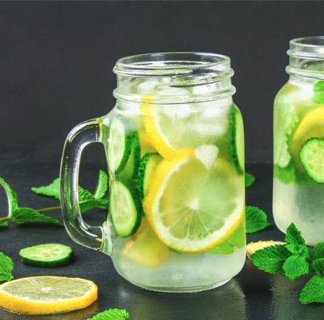 a mason jar filled with water and lemon slices and surrounded by mint leaves