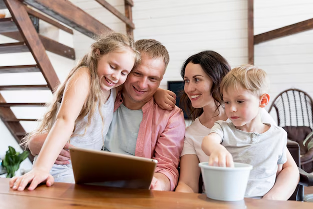 A cute family of four reading something happily on a tablet