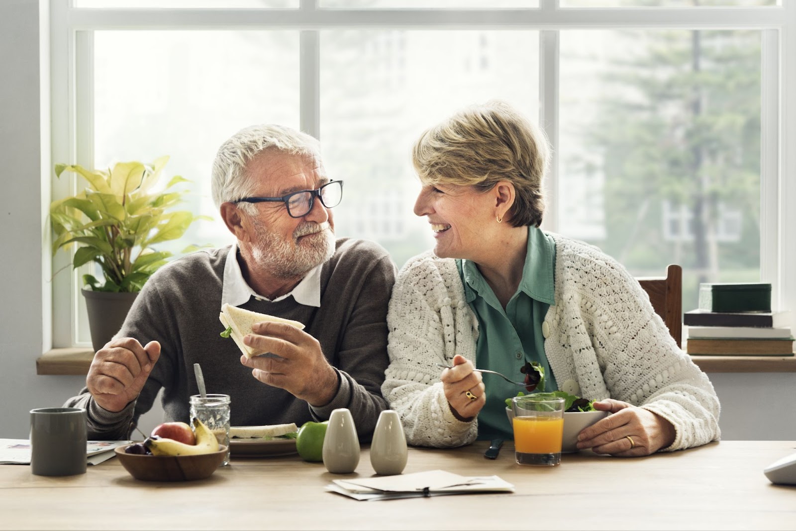 A senior couple smiling at each other while enjoying a healthy meal.