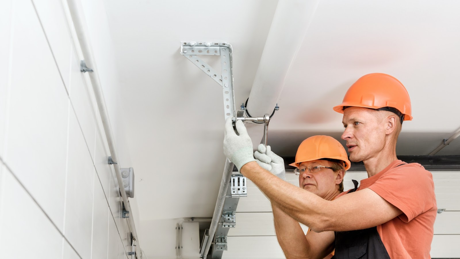 Two professional garage door service provider performing maintenance on the system