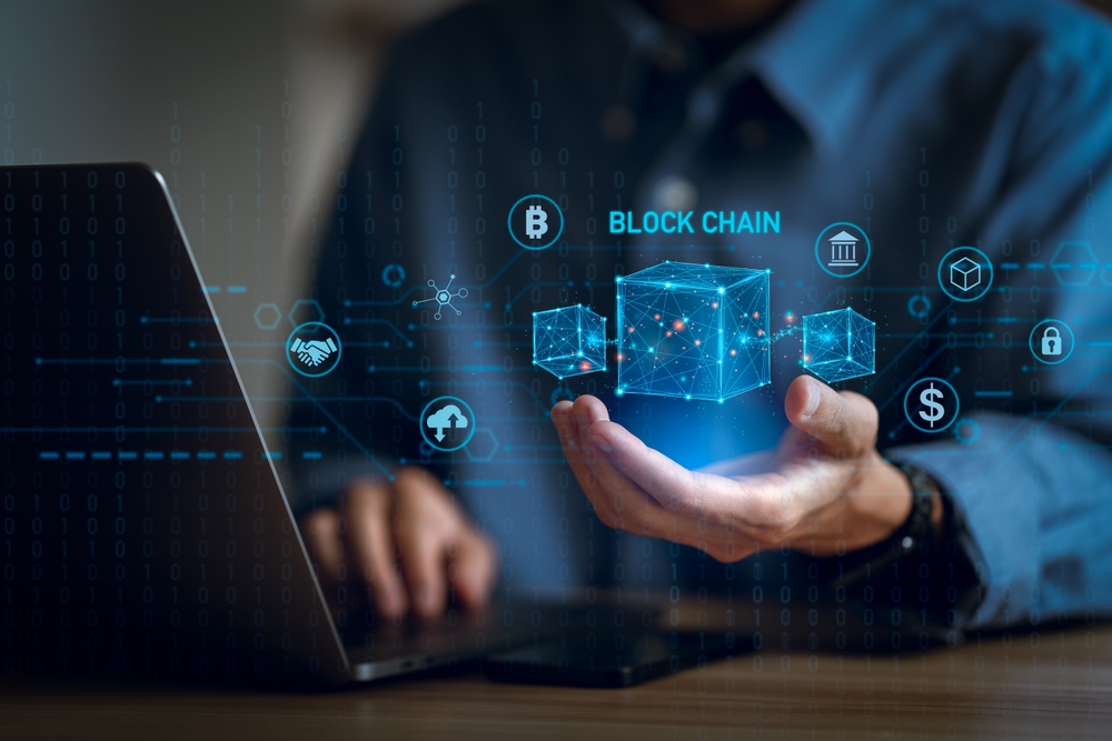 Hand holding visualization of a cube with the word blockchain above it