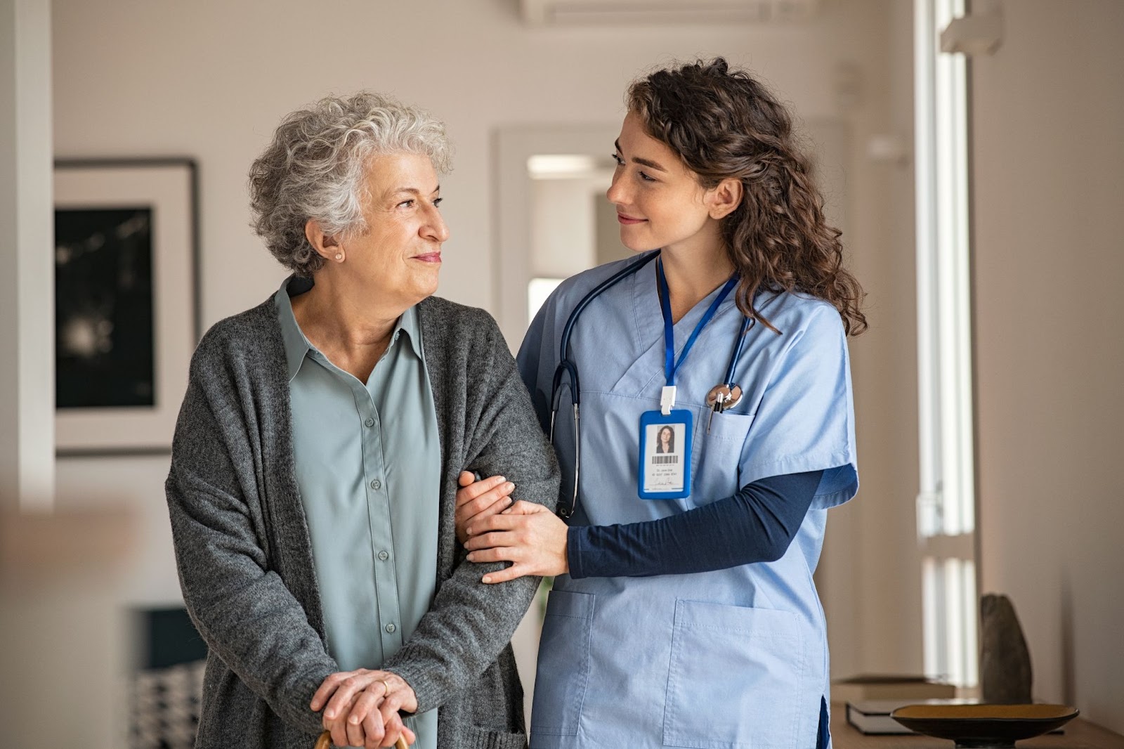 A young nurse and a senior woman smiling at each other in respite care.