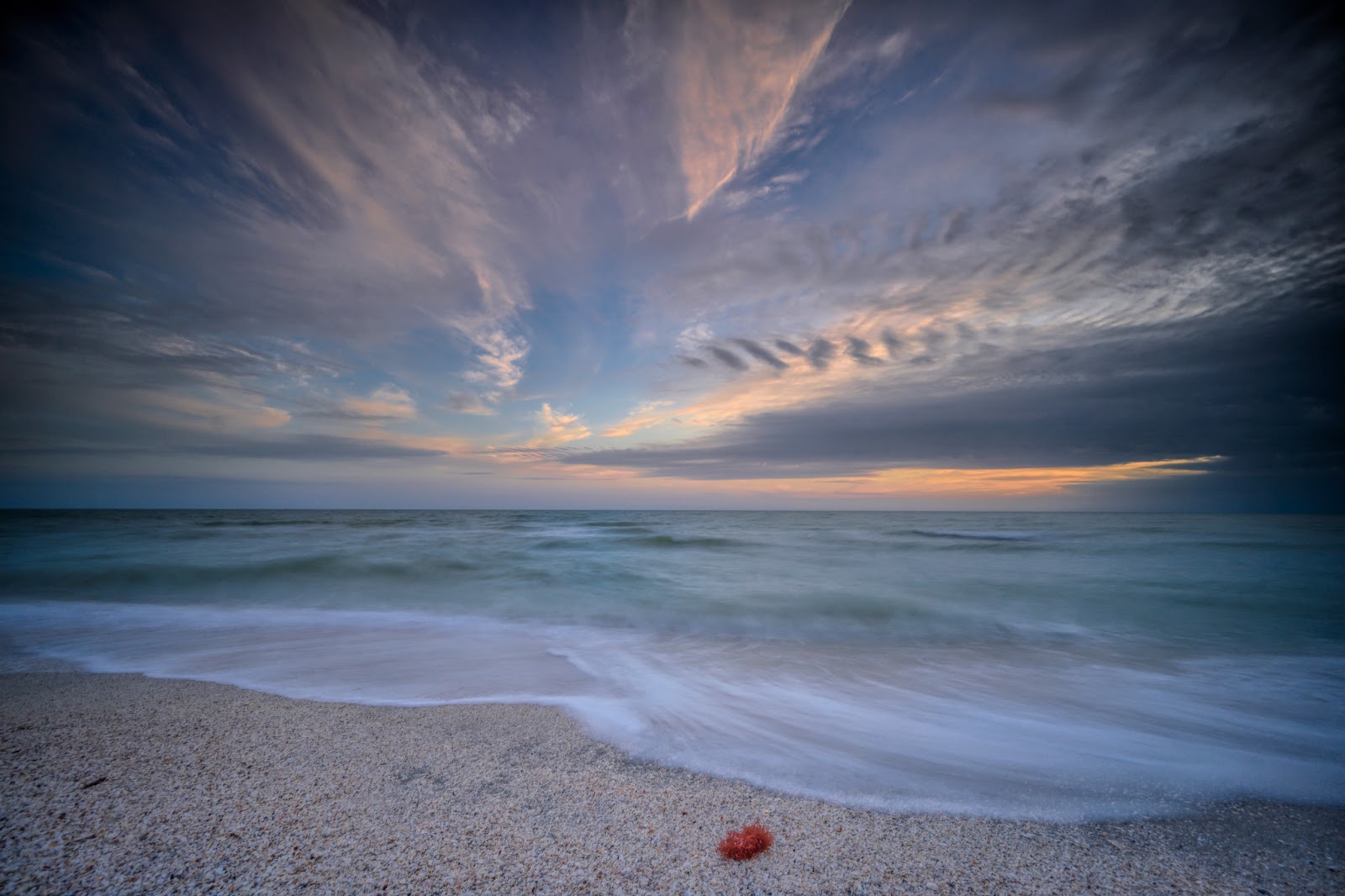 Sunset and soft waves on the white sand