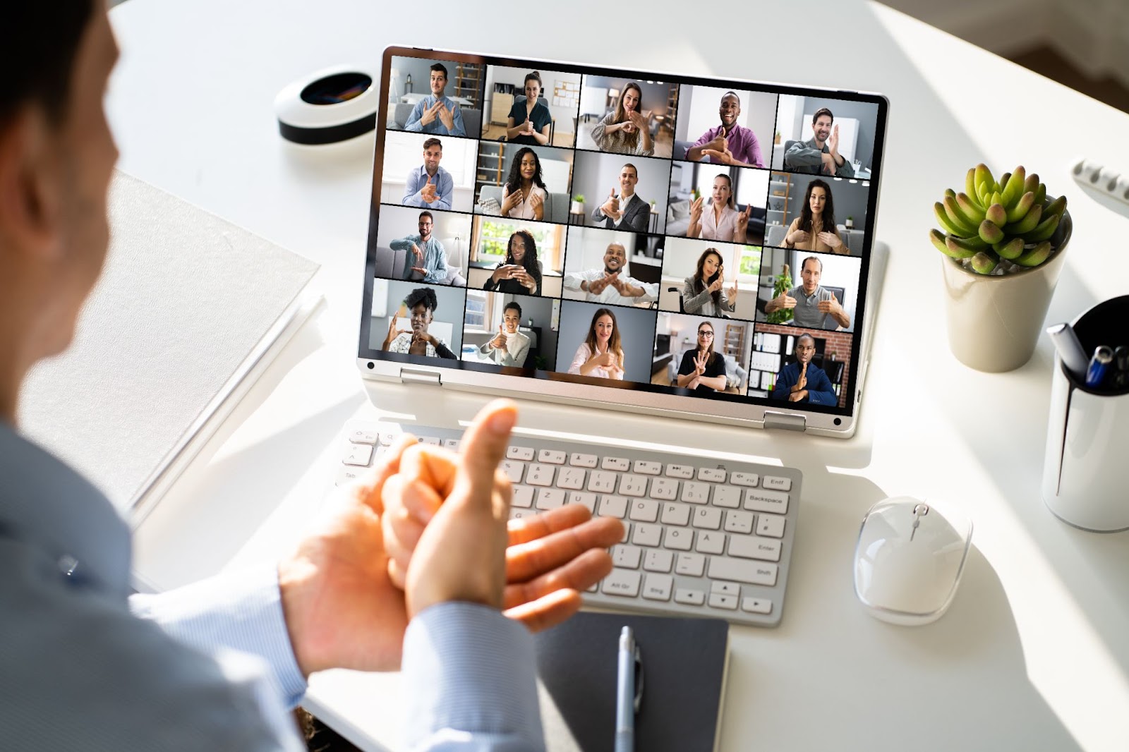 Person attending a virtual meeting on a laptop, with a screen displaying multiple participants in individual video tiles engaging in a lively team debate.