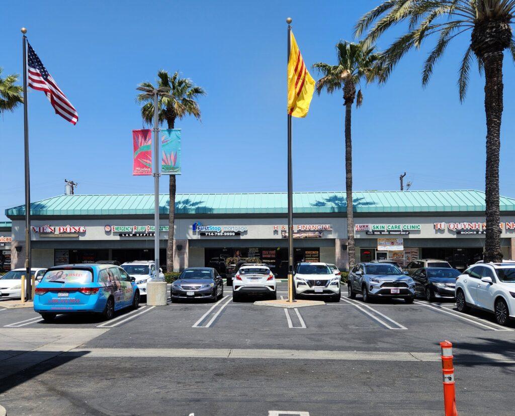 A parking lot with flags and palm trees

Description automatically generated