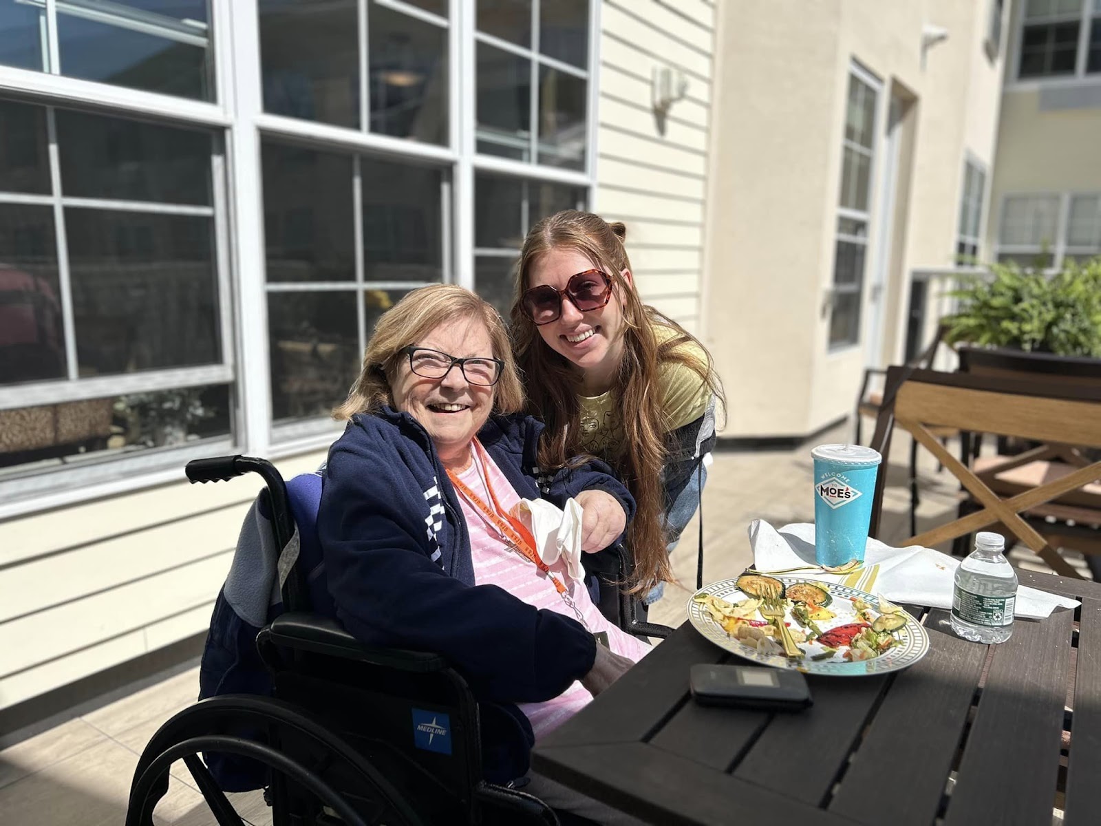 A smiling woman receiving in-home dementia care with a caregiver