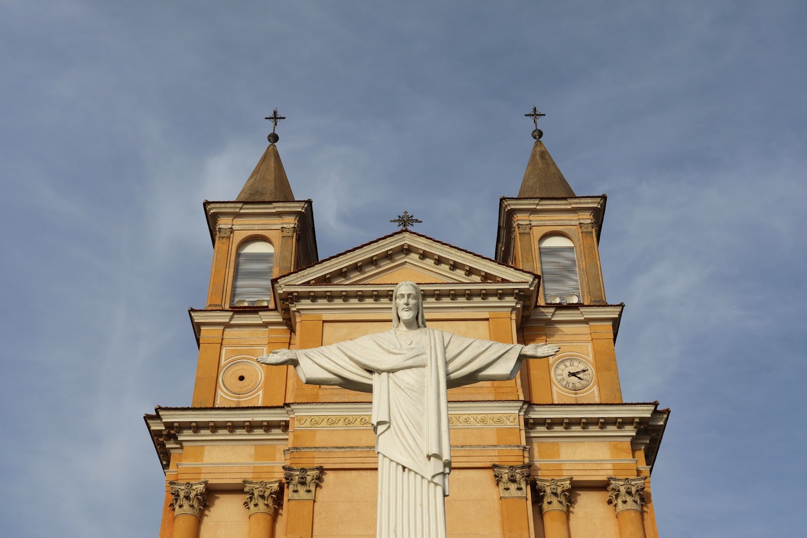 Frente da Igreja Matriz Nossa Senhora do Rosário vista de baixo para cima. Estátua de Cristo Redentor  em frente à igreja.