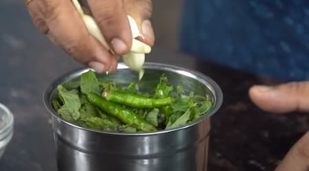 Blending coriander leaves, mint leaves, garlic cloves, jeera powder, salt, green chillies, and water into a smooth paste for Green Mint Chutney.