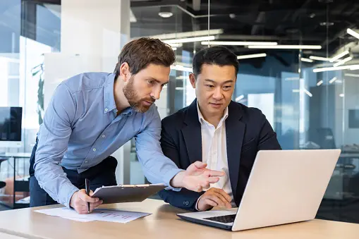 Two men working on business strategy on a laptop and tablet