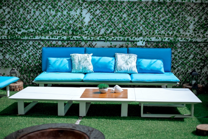 Eine hellblaue Sitzbank im Garten, davor steht ein langer, weißer Tisch