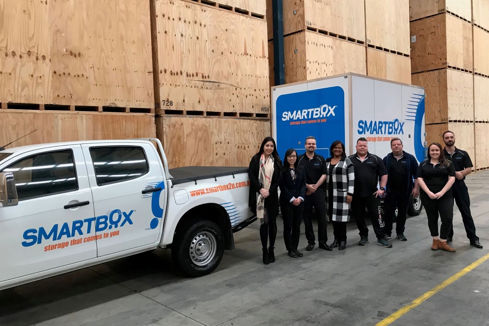 a group of people beside a pickup truck in a storage warehouse