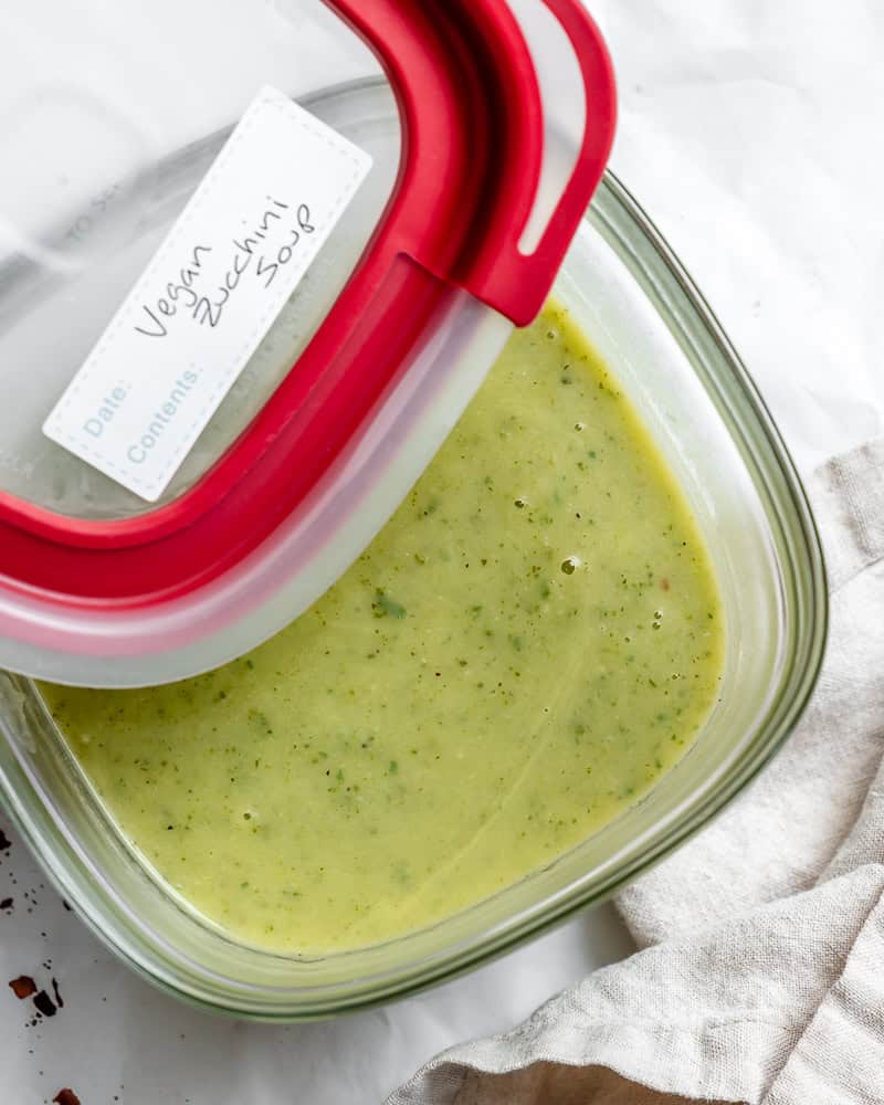 a bowl of vegan zucchini soup in a storage container.