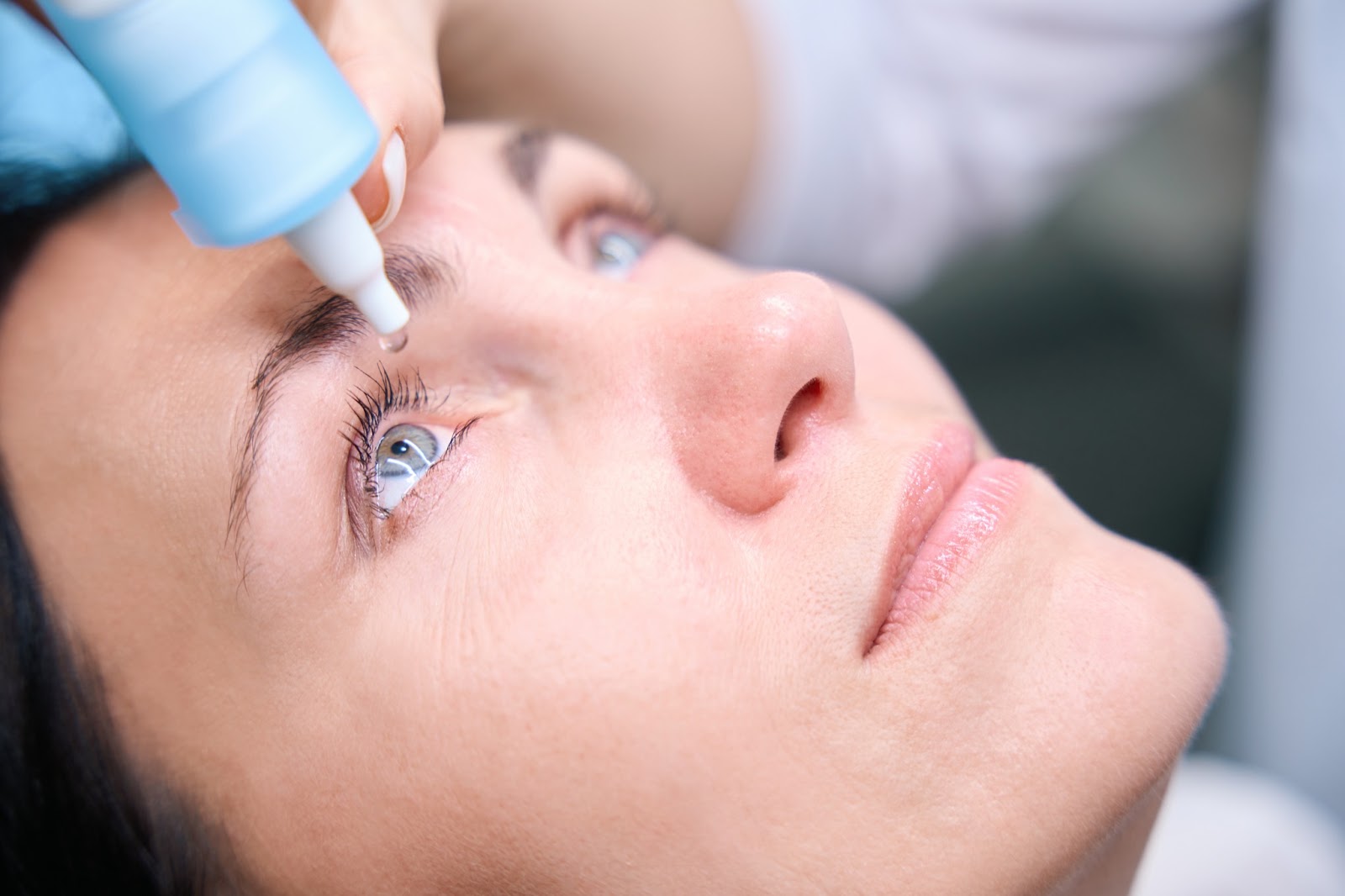 A close up of a woman looking up and getting eye drops for eye dilation