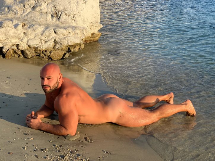 Mister Caccamo lying naked on the beach on his stomach showing off his muscled back and bubble butt for his gay xxx onlyfans subscribers