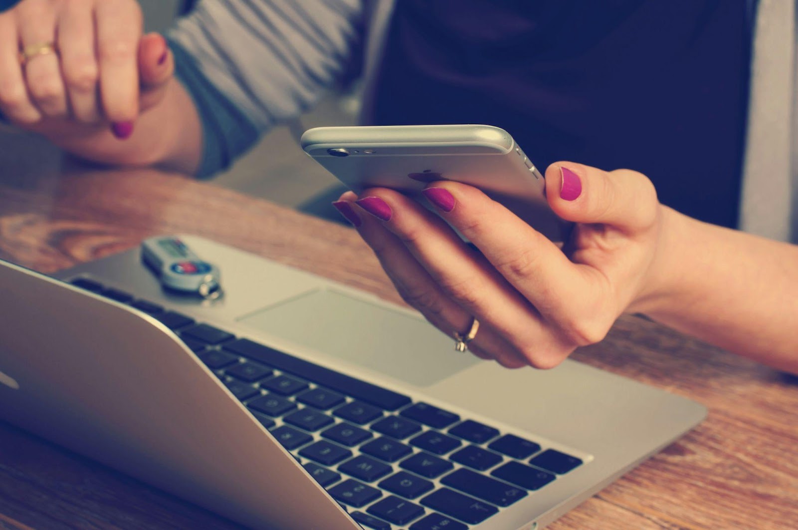 A person holding a phone in front of a laptop