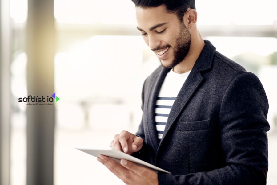 Man using a tablet, smiling in a bright office setting.