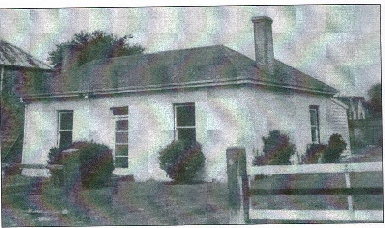 A small white house with a chimney

Description automatically generated