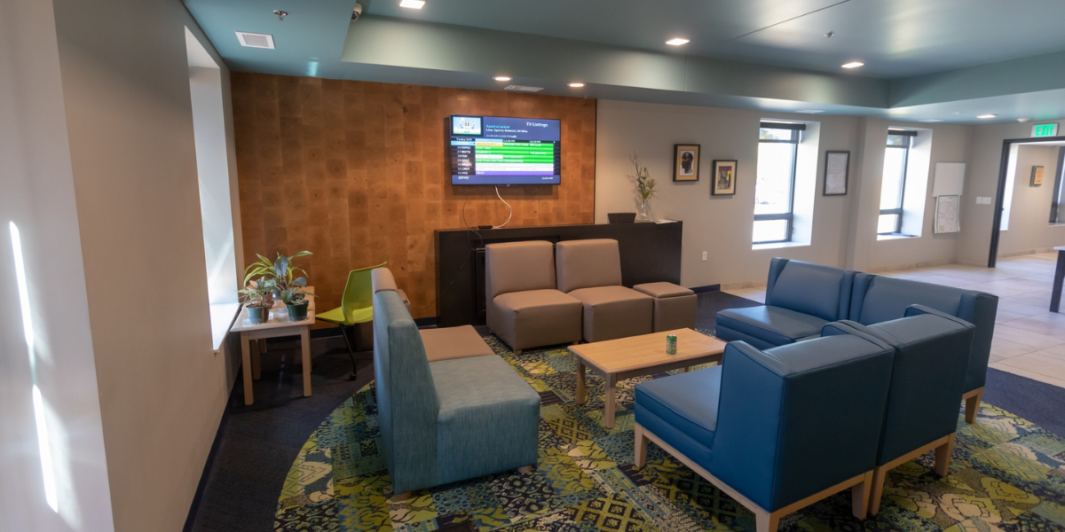 Hotel lobby with blue couches and a TV. Bariatric chairs ensure patient comfort with reinforced structures and wider seats.