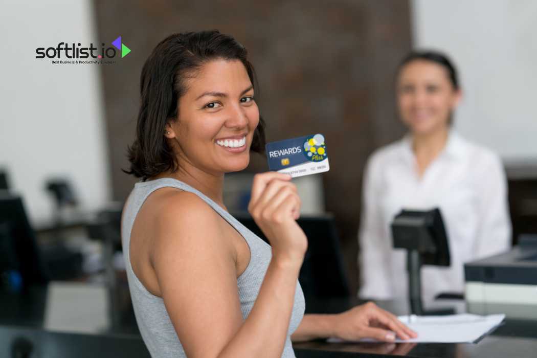 Smiling woman holding rewards card at counter, blurred cashier in background