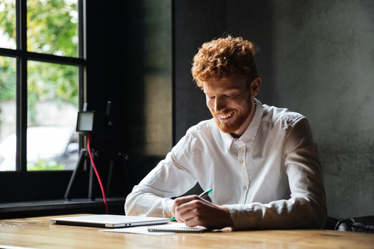 Man smiling while writing on a notepad